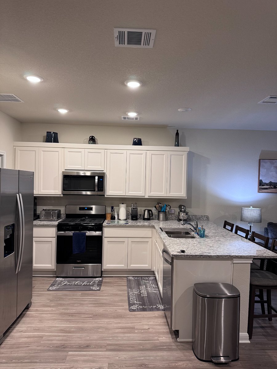 Open concept kitchen fully stocked with utensils, cookware, plates, bowls, cups and coffee maker.