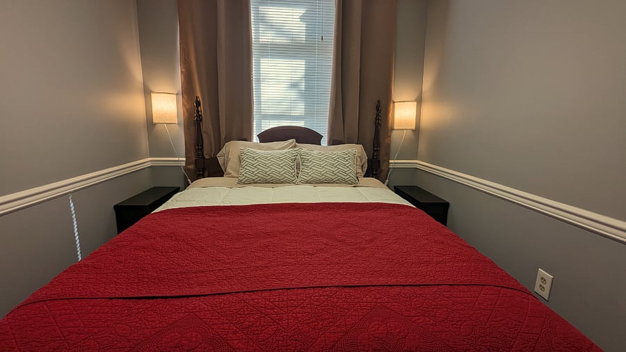 Bedroom with queen size bed and room darkening curtains.