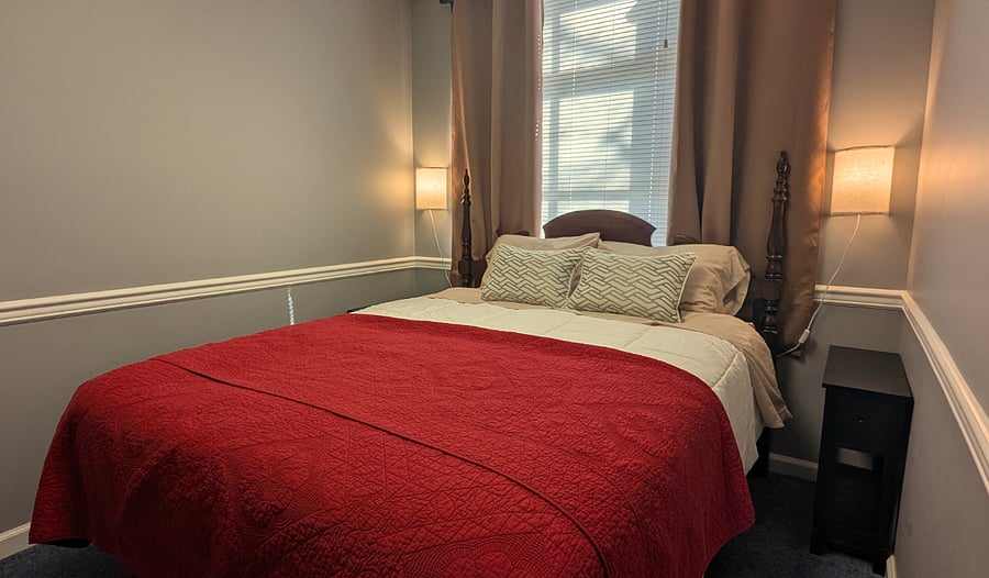 Bedroom with queen size bed and room darkening curtains.