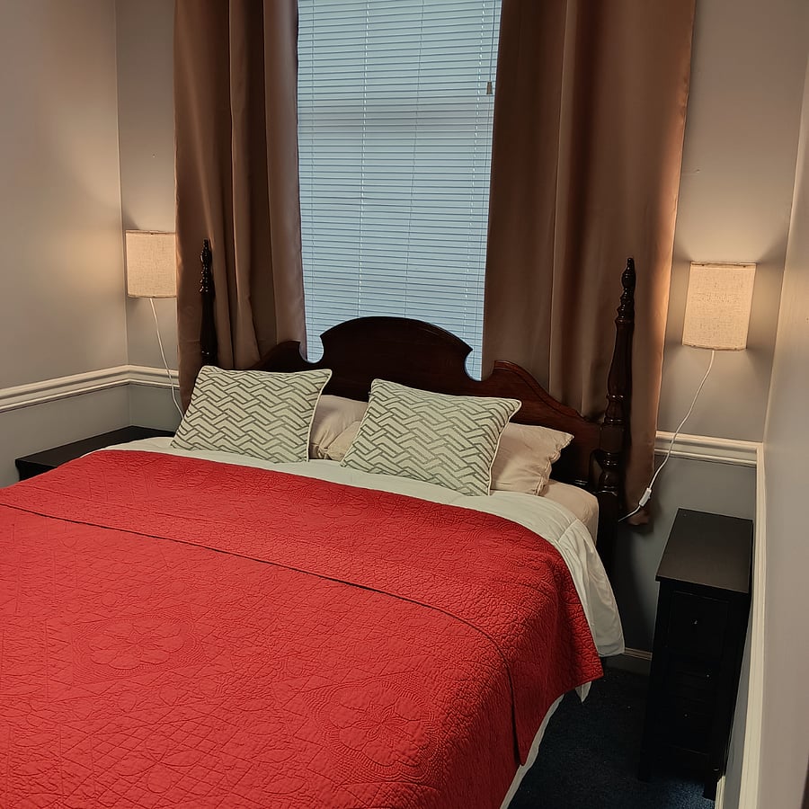 Bedroom with queen size bed and room darkening curtains.