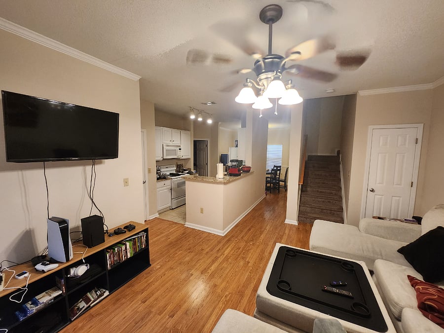 A view of the living room that includes the kitchen, dining room, and stairs.