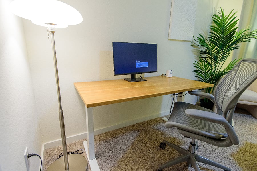 Electric sit/stand desk, external monitor, and ergonomic chair, and a charging station, built for remote work or charting.