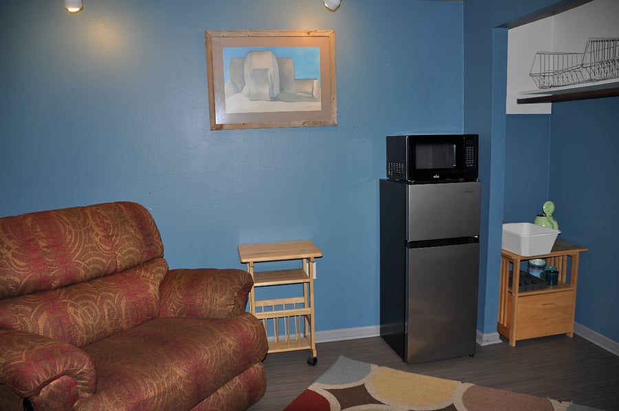 Bonus room with small refrigerator, microwave, electric kettle, double-wide recliner chair, and desk with standing desk adapter.