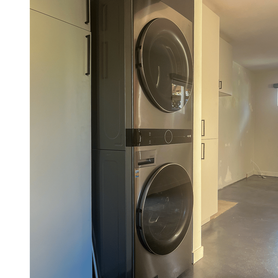 Stainless Steel Full Sized LG Washer and Dryer Stack unit with Hampers for Laundry in adjoining storage closet.