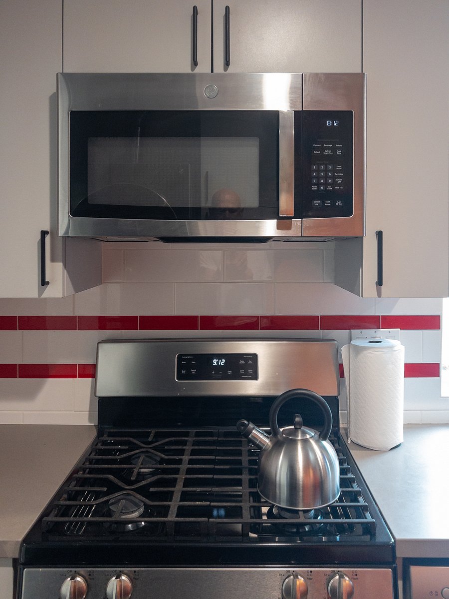 Full-sized GE Stove/Range, Microwave Hood, and dish and glassware storage.