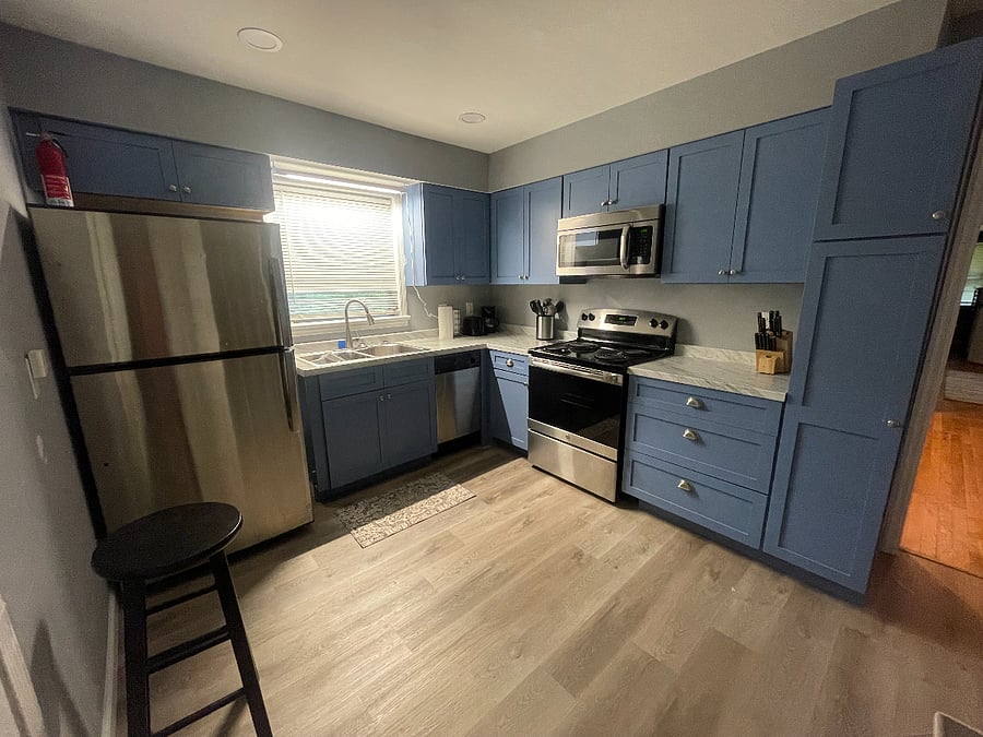 The kitchen is off of the dinning room. It includes stainless steel appliances, ample cabinets, and utensils. The stove is electric.