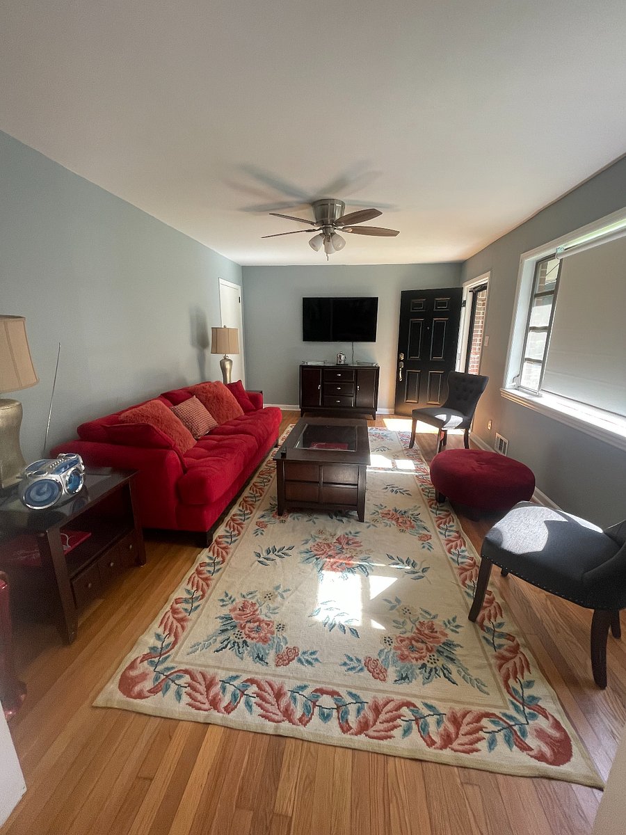 The living room is well lit with windows and seating for at least 5 people.