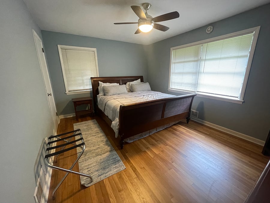 Room 2 is down the hallway. It features a queen sized bed, a Tv, book case, and closet next to the bed.