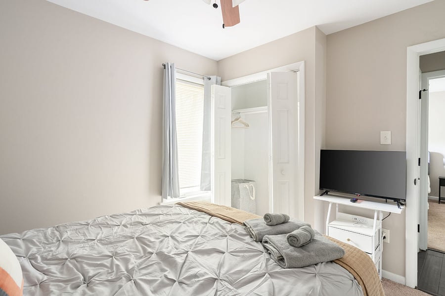 third bedroom with smart TV, closet, ceiling fan and room darkening curtains.