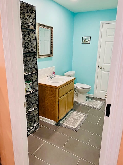 Guest bathroom accessible from kitchen area. Shelving system next to vanity.