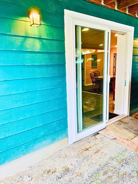 Private entrance via sliding glass door. Underneath second-story deck. The floor of this external area is currently gravel and dirt, unfinished.