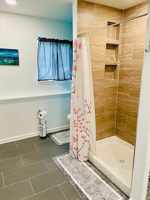 Shower with shelving next to private toilet area.