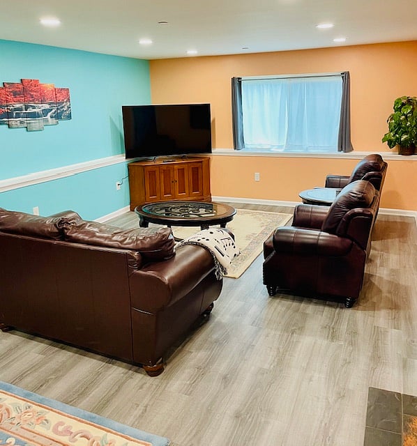 Living area with a loveseat, two recliners, three coffee tables, entertainment center, and a smart TV.