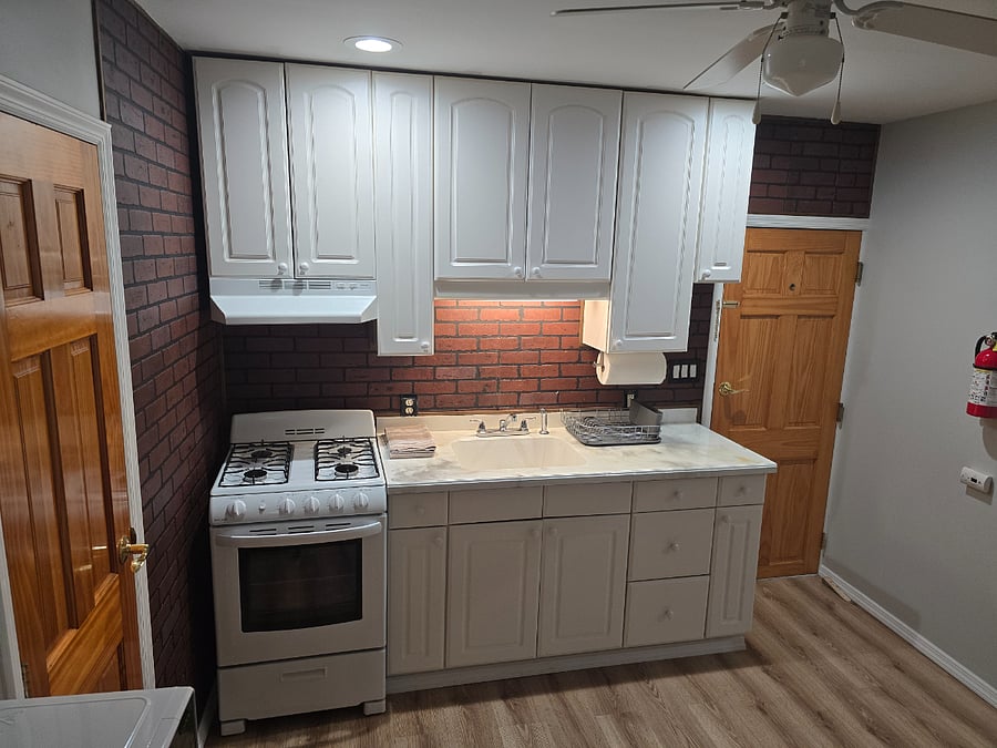 Kitchen counter, sink, stove/oven and back entrance door on top right