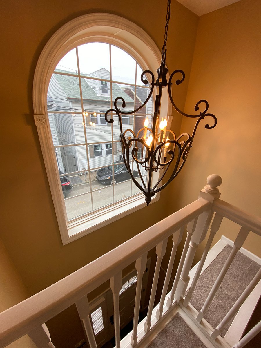 The foyer boasts a wrought iron chandelier, a large arch window, and an open design that brings in plenty of natural light.