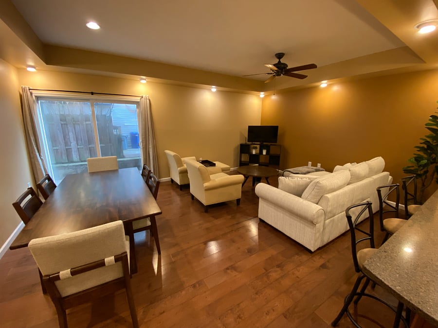 Embrace the open flow of this well-lit interior living and dining area. This inviting space features 9 ft. ceilings, a six-top dining table, a comfortable sofa (which also converts to a bed), and two cozy armchairs. A sliding glass door leads to a small back patio, bringing in natural light. The convenient bar area offers a seamless connection to the kitchen, perfect for socializing. Ready to relax and connect? The living area comes equipped with included WiFi and a TV with Roku, perfect for streaming your favorites!