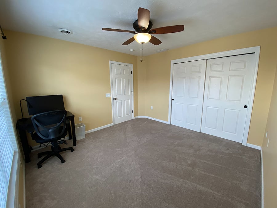 The secondary bedroom - now furnished with a queen bed (not pictured) - features ample natural light, a ceiling fan, plenty of closet space, and a dedicated workspace.