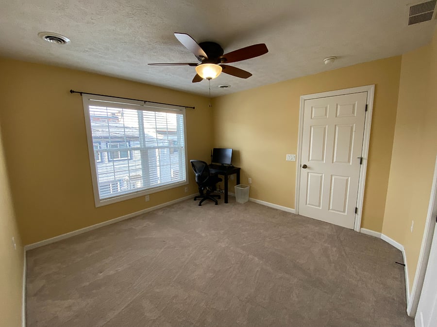 The secondary bedroom - now furnished with a queen bed (not pictured) - features ample natural light, a ceiling fan, plenty of closet space, and a dedicated workspace.
