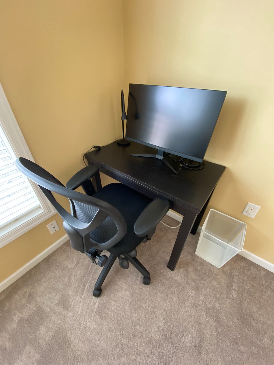 The secondary bedroom offers a dedicated area for a desk setup, including a small table, desk chair, monitor, task lamp, and waste basket perfect for work, study, or hobbies.