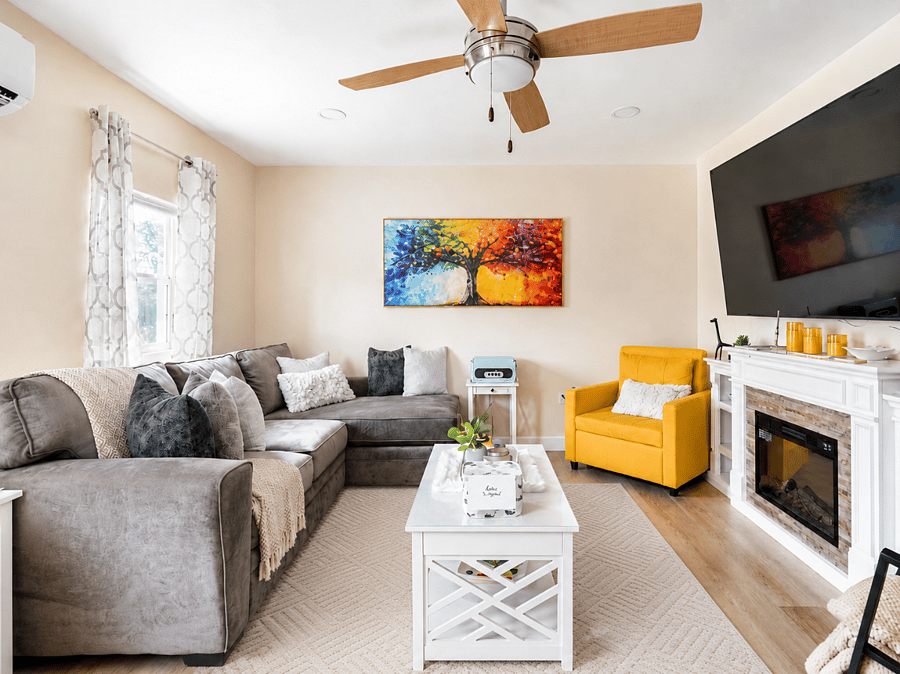 Living area with sectional seating, 70inch Smart TV, and electric fireplace.