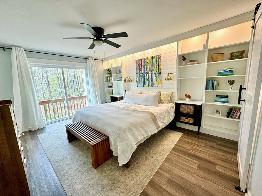 Master bedroom with king sized bed, built in bookshelves, and sliding door to the back porch. 