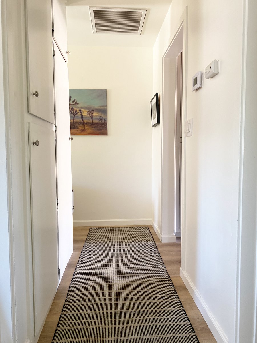 Hallway leading to guest bedrooms and entry with a linen closet