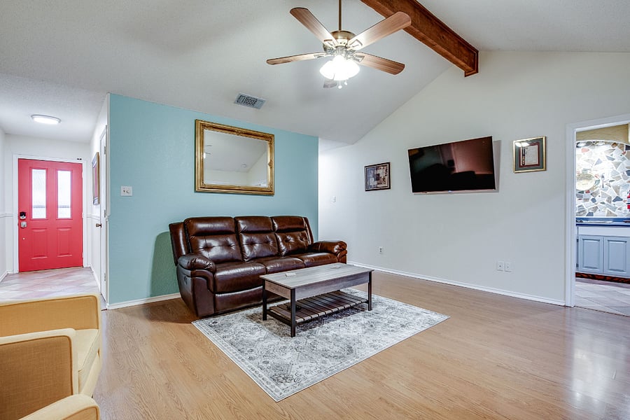 Living room has a couch and loveseat, with vaulted ceiling, ceiling fan, 55" smart TV, and wood fireplace