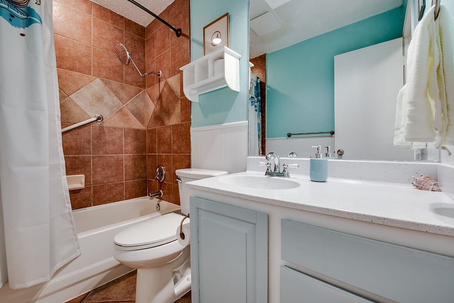 Guest bathroom with tub and shower, adjacent to two guest bedrooms.