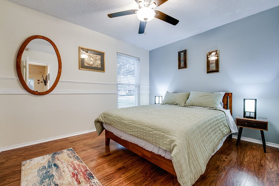 Bedroom 2, with queen bed, ceiling fan, smart TV, closet, and view of front yard.