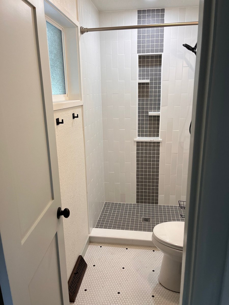 Custom tile, new privacy window glass, removable shower head and vanity with large mirror and new light fixture.