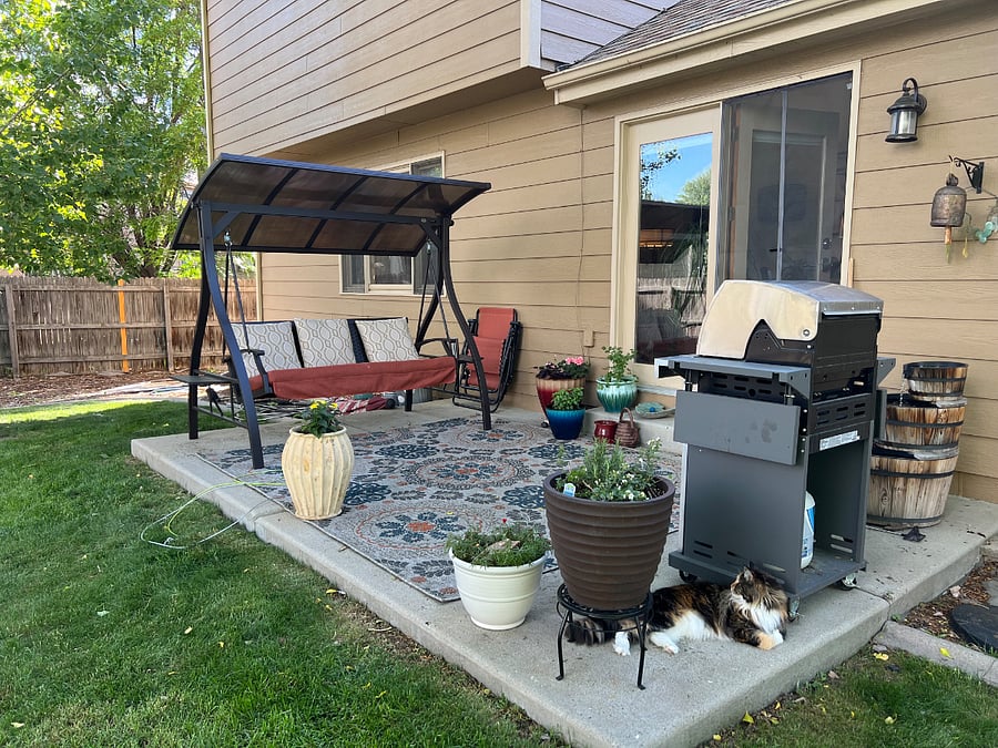 Patio with swing and gas grill. Shaded in afternoon.