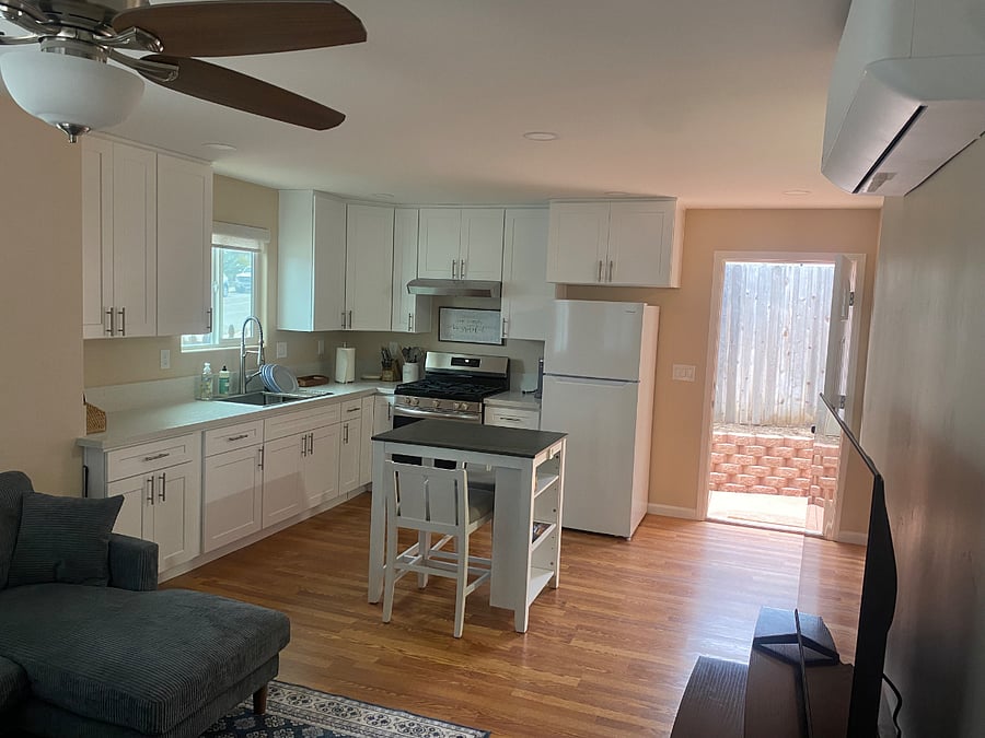 View of the full kitchen with front door open to the right.