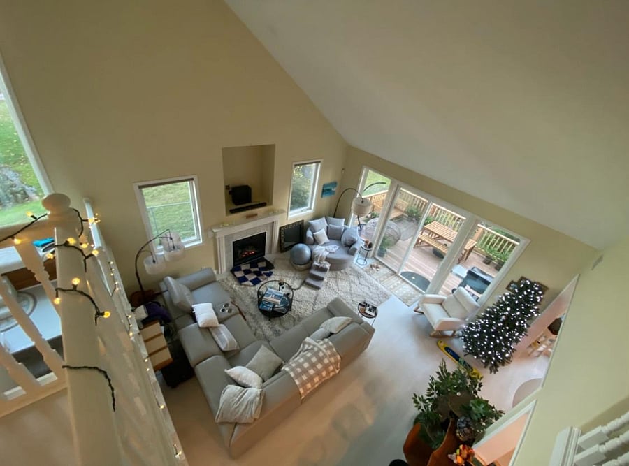 Living room shot from the second floor showing windows, deck, fireplace and couch