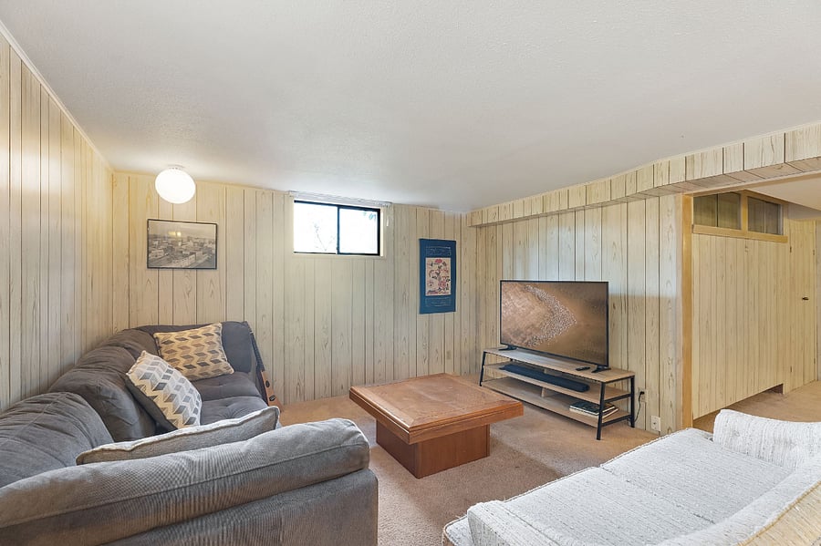 Living room in the basement. Lush carpet, comfortable couches, 55" Smart TV with Yamaha Soundbar