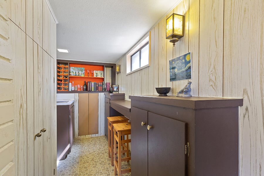 Mini-bar nook off the basement living area complete with sink, wine rack, and bar stools
