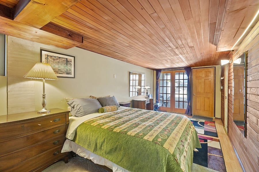 Basement bedroom with Queen size bed, private access, cedar panelling, and french doors