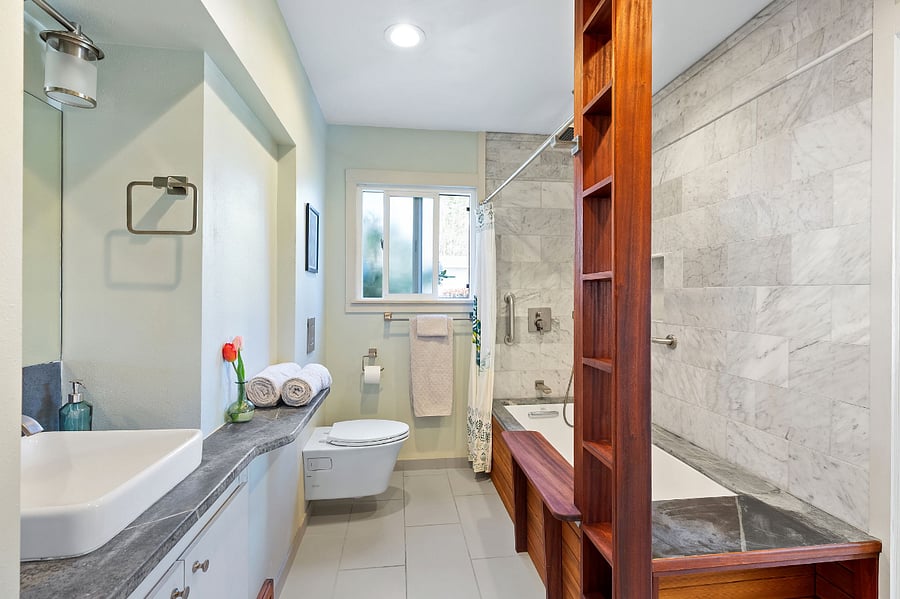 Luxurious primary bathroom, newly remodeled with rain shower, Carrera tile, Epay wood, soapstone counter and bathtub rim.