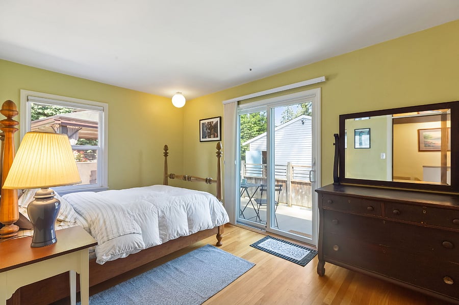 Second bedroom with lots of light, antique chest of drawers, sliding doors to the back deck and yard.