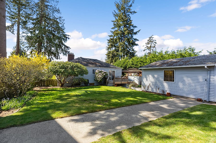 View of the backyard with shuffleboard court, garage to the right and deck/house to the left.
