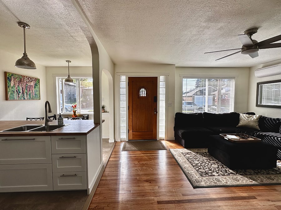 Sun-filled open-concept living room and kitchen. Hardwood floors and a stylish ceiling fan.