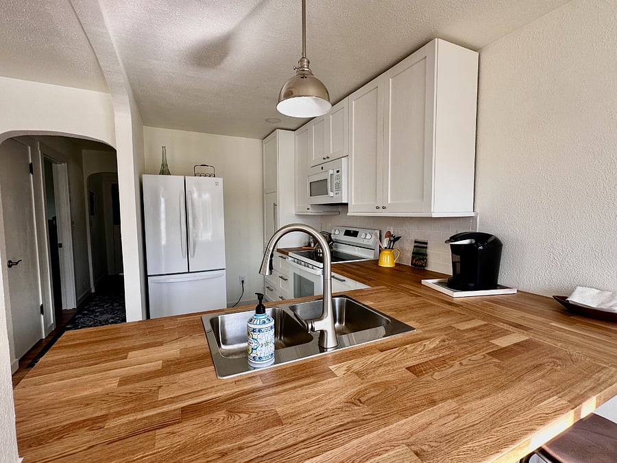 Enjoy cooking in this fully equipped kitchen featuring updated appliances, butcher block countertops, and a clean, modern design.