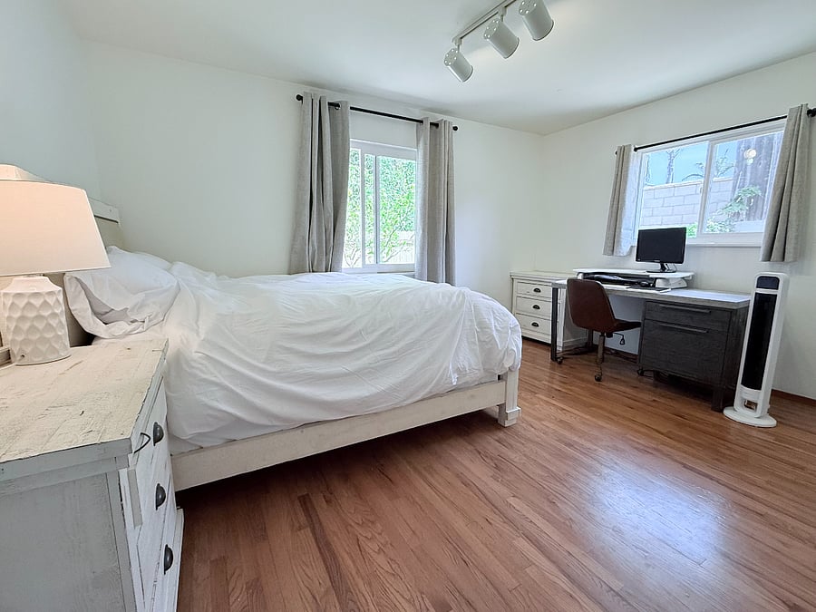 Queen bedroom with work station, featuring sit/stand desk and monitor.