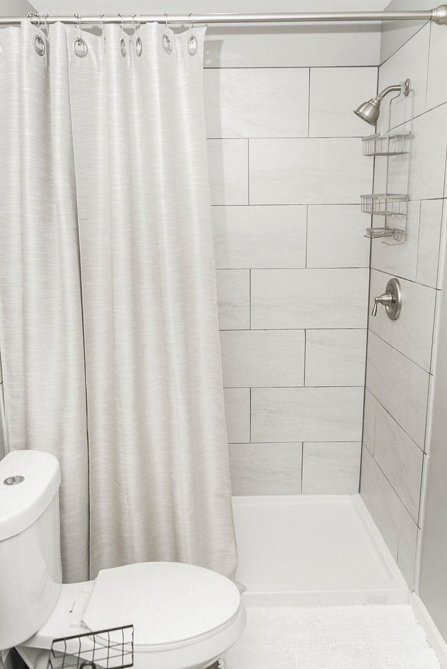 Clean and sleek bathroom with a tiled walk-in shower, rainfall showerhead, and fresh white accents.