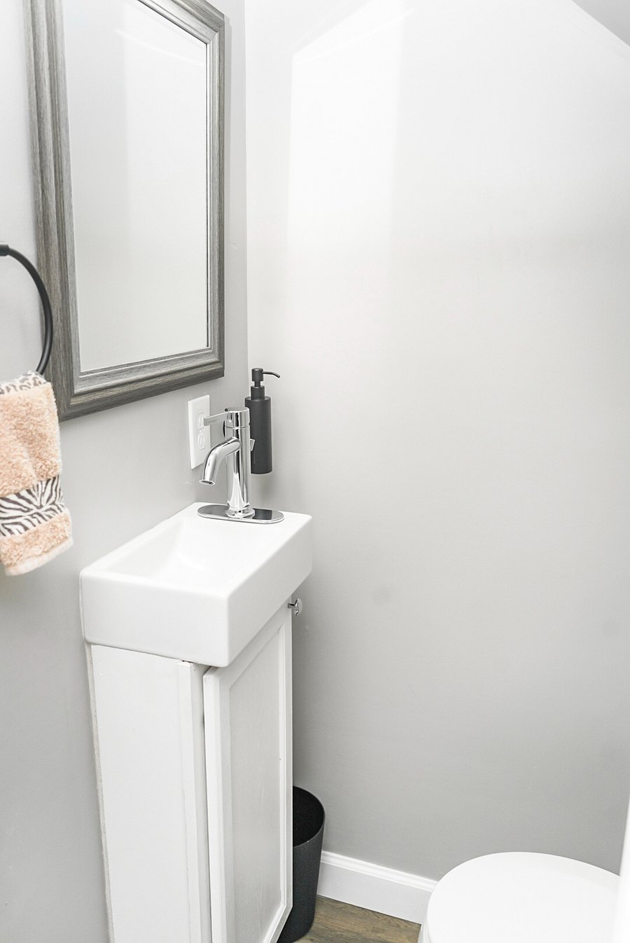 Minimalist half bath with a modern sink, stylish mirror, and essentials within easy reachperfect for guests.