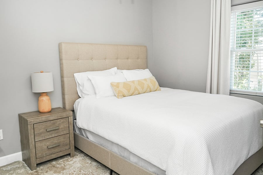 Warm and inviting bedroom with neutral tones, a plush bed, and natural light for a calming retreat.