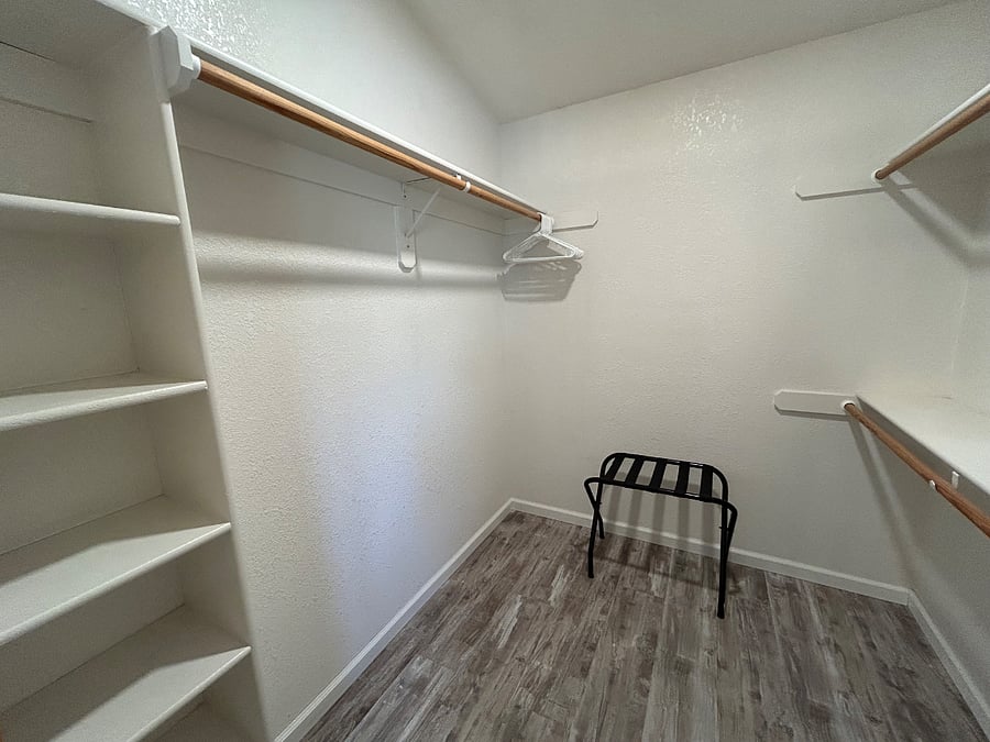 This walk-in closet in the bedroom suite has floor to ceiling shelves on both sides and over 12 feet of rod space.