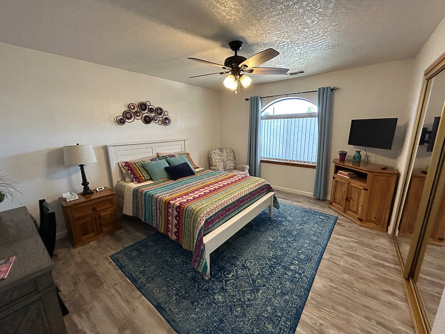 At the front of the house, this bedroom faces south. It has a queen bed, recliner, writing desk, and sliding mirror doors, behind which you'll find shelves and over 10 feet of rod space.