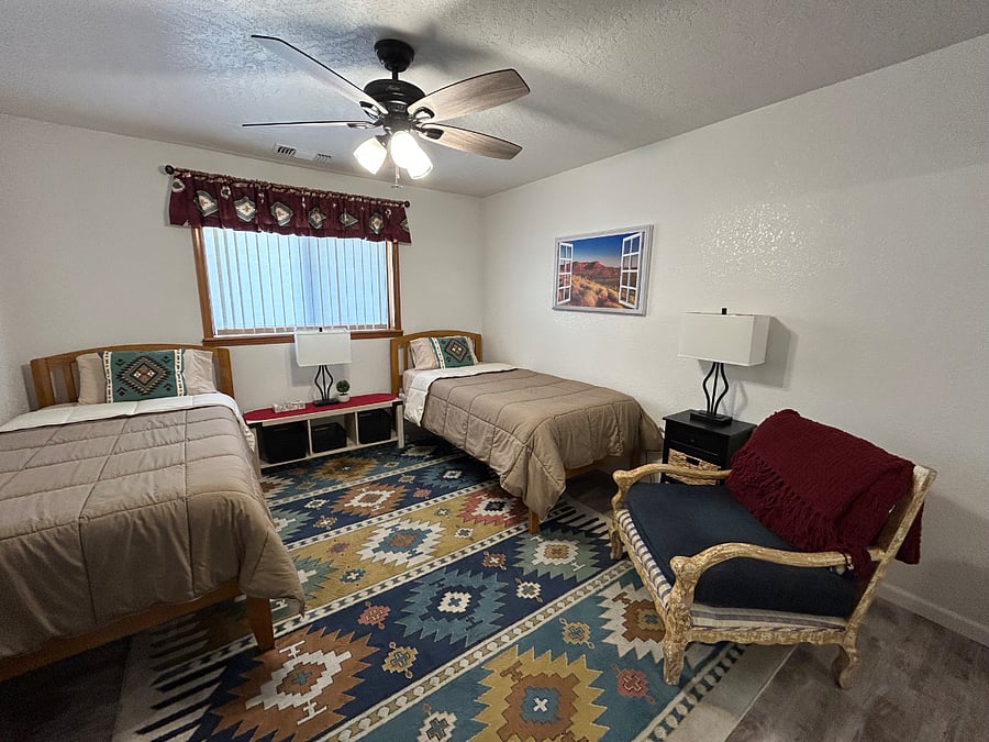 This bedroom is at the back of the home across from the front bedroom. It has two extra-long twin beds, a tall chest of drawers, a big comfy chair, and a large closet with cubbies and 6 feet of rod space.