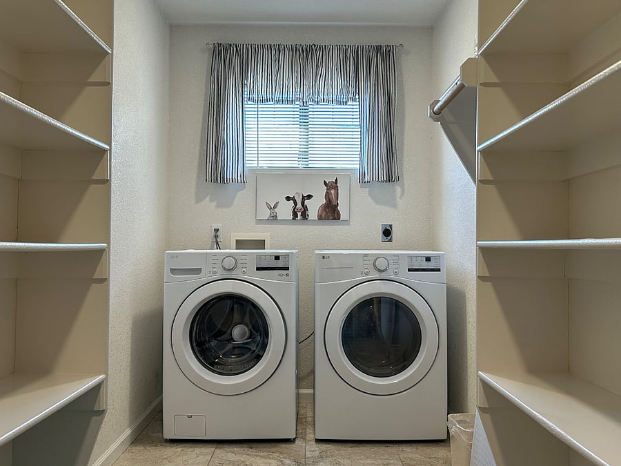 Front-loading washer and dryer, hanging rack, full-size ironing board, and iron in the laundry room as well as lots of storage space.