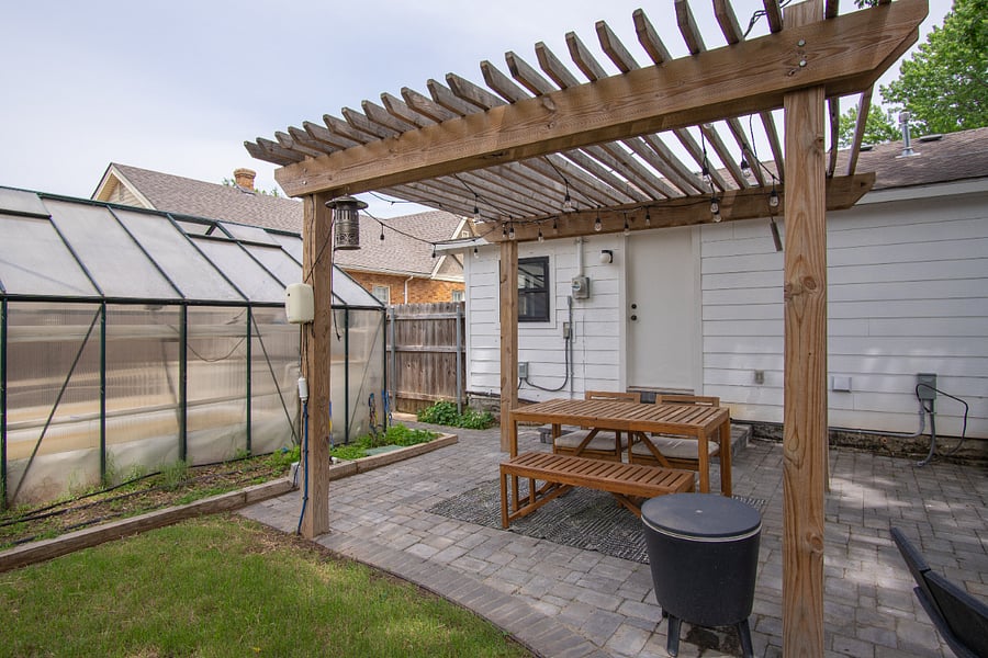 Backyard feat. outdoor dining space and greenhouse